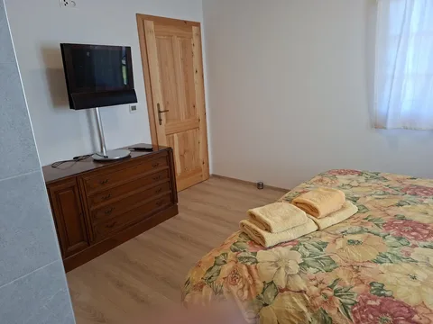 Schlafzimmer mit floralem Doppelbett, Kommode und Fernseher